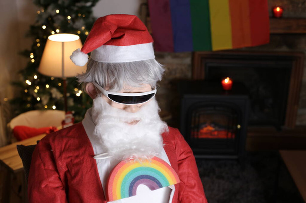 portrait de personne en costume de Père Noël et lunettes de soleil élégantes et lgbtq signe arc-en-ciel à l'intérieur - Photo, image