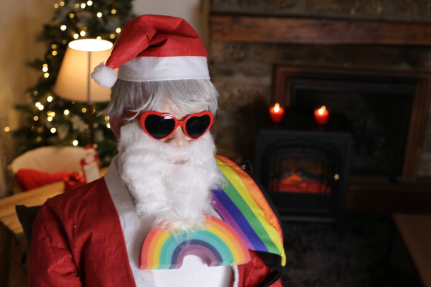 portrait de la personne en costume de Père Noël et en forme de coeur lunettes de soleil et lgbtq signe arc-en-ciel à l'intérieur - Photo, image