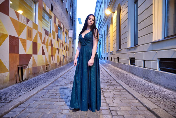 Wroclaw city, young woman posing in the evening. Brunette female model with long, green dress. - Fotografie, Obrázek
