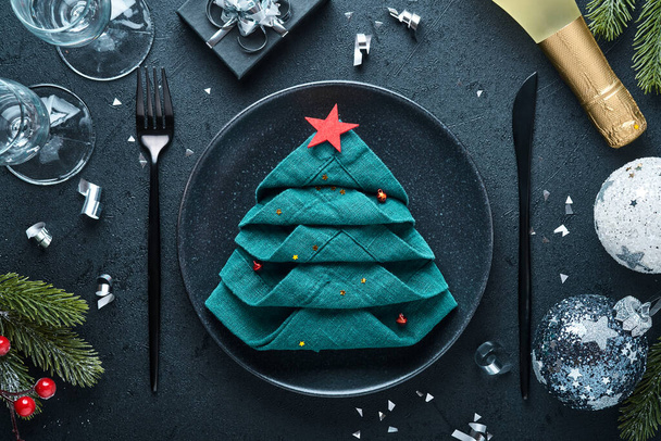 ブラックシルバーウェアで黒の色を設定クリスマステーブル、クリスマスツリーとして折り畳まれたナプキン、クリスマスシルバーボール、シャンパン、クリスマスの挨拶のための黒の背景に眼鏡。テキストの空のスペース. - 写真・画像