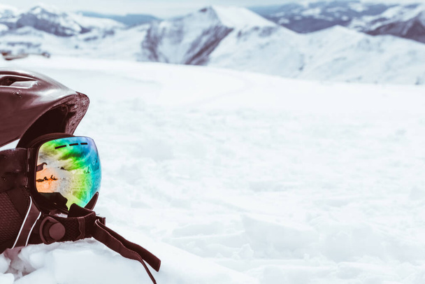 Casco negro con gafas de esquí en la nieve con fondo blanco nevado montañas paisaje - Foto, Imagen