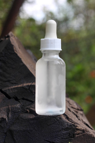 A clear bottle with a dropper standing in the natural environment  - Photo, image