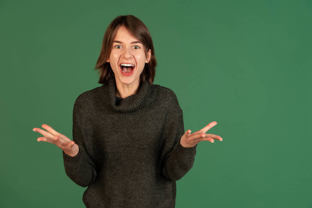Cropped portrait of young beautiful woman, laughing in excitement isolated over green background - Photo, Image