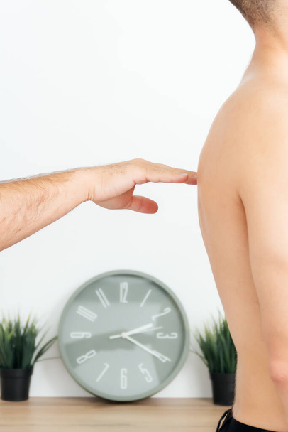 osteopath checks man's back with palm of his hand, young man stands sideways - Foto, Imagen