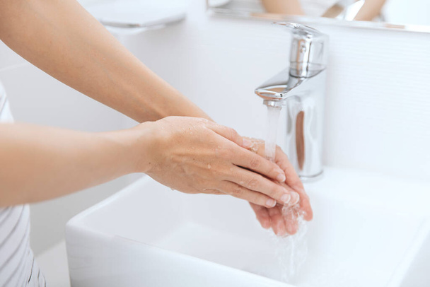 Handen wassen onder de stromende kraan. Handen wassen wrijven met zeep voor preventie van corona virus, hygiëne om te stoppen met het verspreiden van corona virus in of openbare wasruimte. Hygiëne concept hand detail - Foto, afbeelding