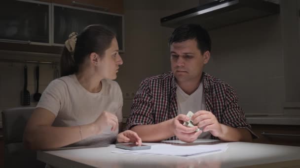 Stressed young couple calculating monthly loan or credit payment on kitchen at night. Concept of financial difficulties, poverty, bankruptcy, taxes and rent payment. - Footage, Video
