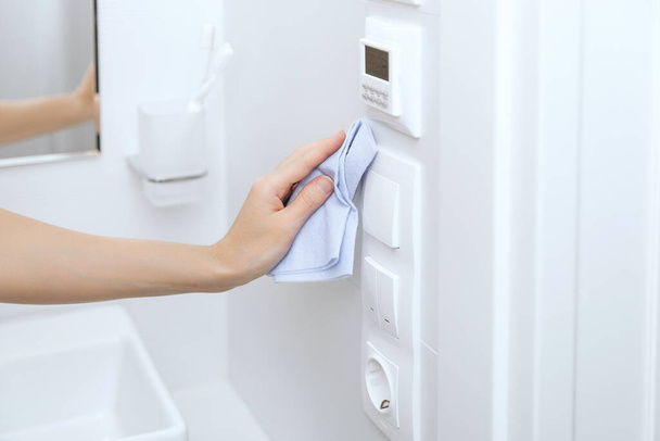 Cleaning switches and sockets with a microfiber cloth. Sanitize surfaces prevention in hospital and public spaces against corona virus. Woman hand using wet wipe for cleaning home room door link - Foto, Imagen