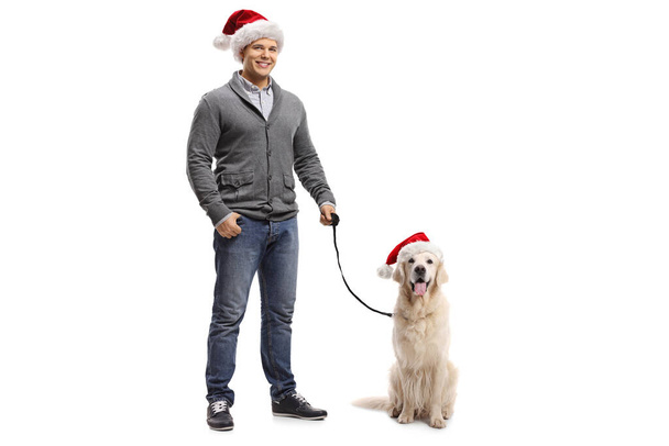 Full length portrait of a young man and a labrador retriever dog with santa cluas hats isolated on white background - Fotoğraf, Görsel