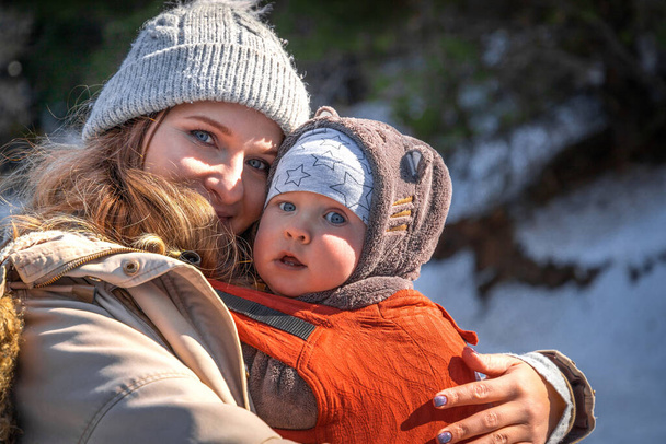 jong Kaukasisch blond moeder met zijn baby jongen in ergonomische baby drager in de winter outdoor. - Foto, afbeelding
