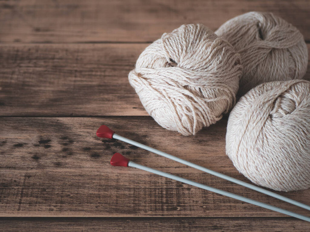 Yarn and needles for knitting, close up. Balls of thread and knitting needles on wooden background - Fotografie, Obrázek