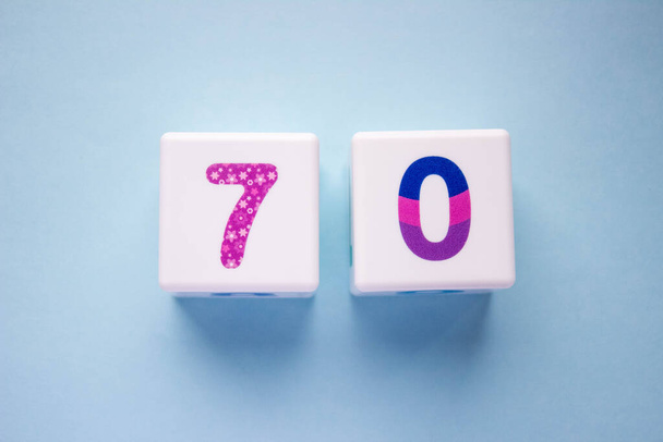 Close-up photo of a white plastic cubes with a colorful number 70 on a blue background. Object in the center of the photo - Valokuva, kuva