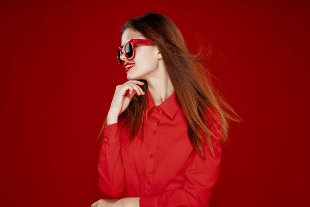 vonzó nő piros ing napszemüveg divat piros háttér - Fotó, kép