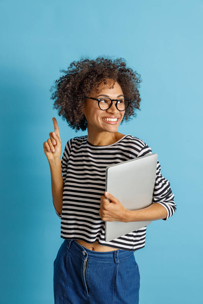 Joyful young woman with laptop pointing finger up - Photo, image