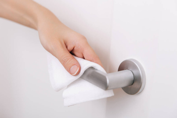 Cleaning door handles with an antiseptic wet wipe and gloves. Sanitize surfaces prevention in hospital and public spaces against corona virus. Woman hand using towel for cleaning home room door link - Foto, Imagen