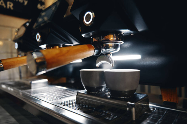 Horizontální fotografie stroje na espresso pracující s interiérem baru na pozadí - Fotografie, Obrázek