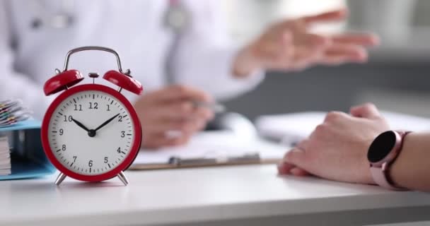 Γιατρός διεξάγει μια ιατρική συμβουλή στον ασθενή με φόντο το ξυπνητήρι - Πλάνα, βίντεο