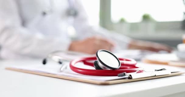Stetoskooppi sijaitsee lääketieteelliset asiakirjat taustalla työskentelevät lääkäri - Materiaali, video