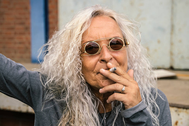 Gyönyörű nő hosszú, göndör hajjal A nő előhúz egy cigarettát.  - Fotó, kép