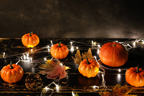 Pumpkins and glowing lights on dark wooden background - Photo, image