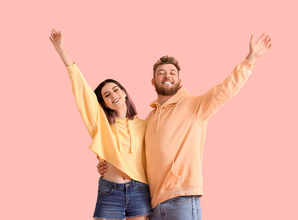 Cool happy young couple in hoodies on color background - Foto, imagen