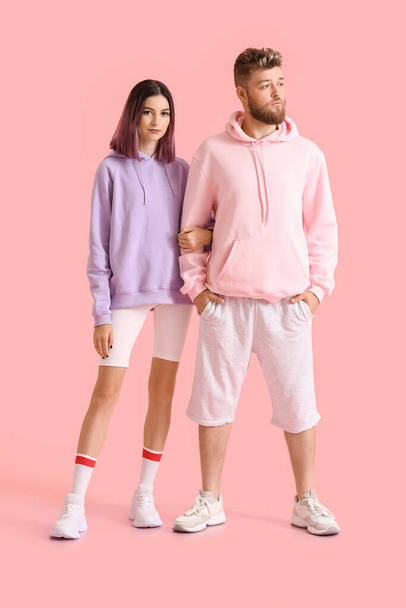 Cool young couple in hoodies on color background - Fotoğraf, Görsel