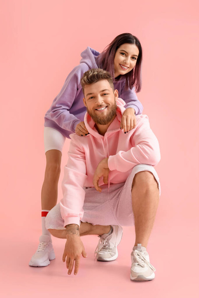 Cool young couple in hoodies on color background - Fotografie, Obrázek