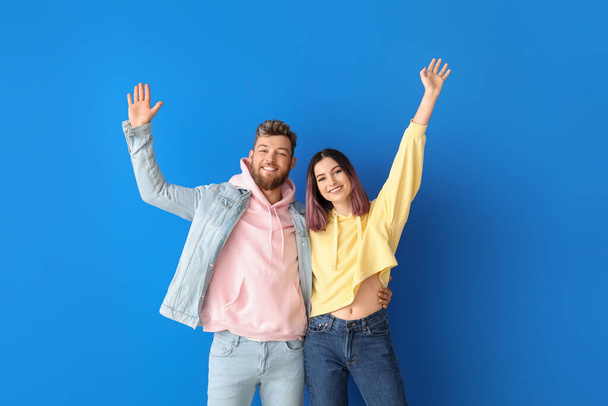 Cool gelukkig jong paar in hoodies op kleur achtergrond - Foto, afbeelding
