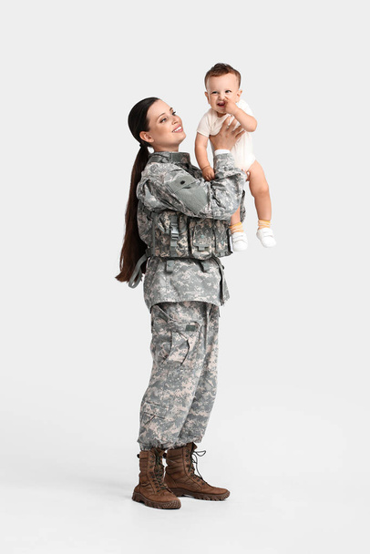 Vrouwelijke soldaat met haar kleine zoon op lichte achtergrond - Foto, afbeelding