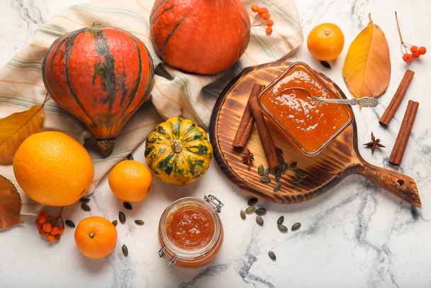 Bowl and jar of sweet pumpkin jam with oranges on white marble background - Photo, Image