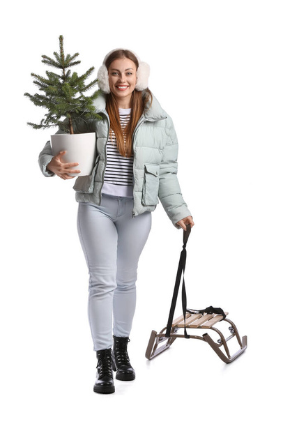 Mujer joven con trineo y árbol de Navidad sobre fondo blanco - Foto, Imagen