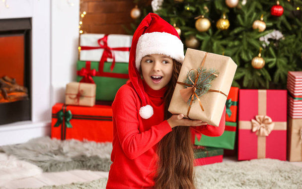 Surprised little girl with gift at home on Christmas eve - Foto, Imagen