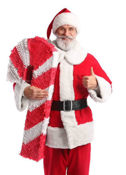 Santa Claus con piñata de bastón de caramelo mostrando el pulgar hacia arriba sobre fondo blanco - Foto, Imagen