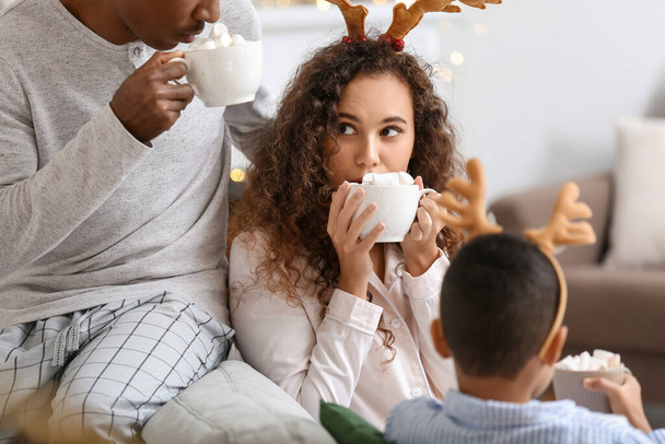 Mutlu Afro-Amerikan ailesi Noel arifesinde evde lezzetli sıcak çikolata içiyor. - Fotoğraf, Görsel