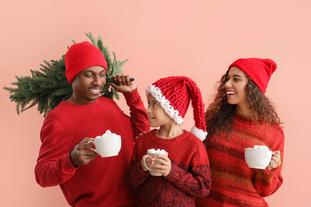 Αφρο-αμερικανική οικογένεια με χειμωνιάτικα ρούχα, με νόστιμη ζεστή σοκολάτα και χριστουγεννιάτικο δέντρο στο φόντο χρώμα - Φωτογραφία, εικόνα