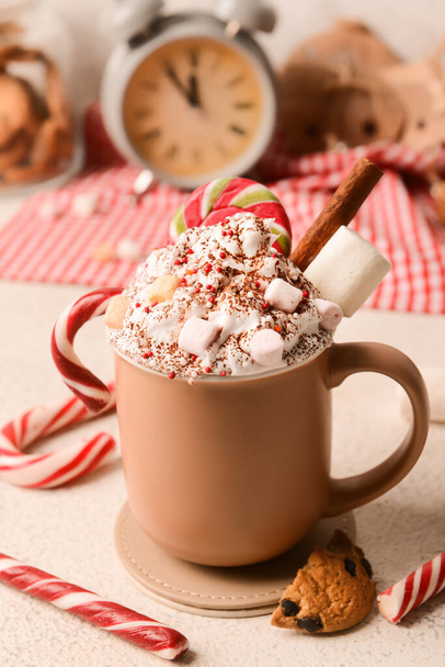 Cup of tasty cacao with candy canes and marshmallows on light background - 写真・画像