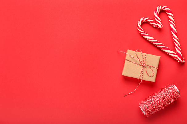 Christmas gift, heart made of candy canes and rope on red background - Foto, Imagem