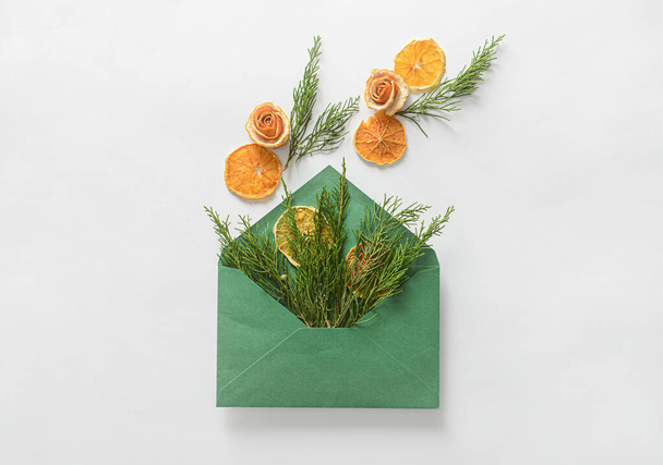 Composition avec enveloppe, branches de conifères, tranches d'orange séchées et écorce sur fond blanc - Photo, image