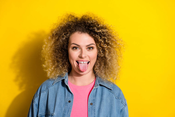Photo of funny coquettish lady stick-out healthy tongue wear denim jacket isolated yellow color background - Фото, изображение