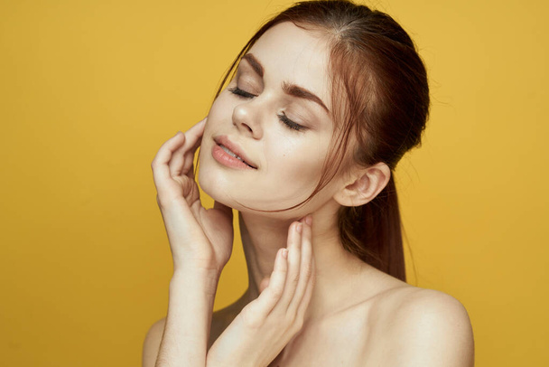 woman with bare shoulders clean skin hairstyle posing yellow background - Zdjęcie, obraz