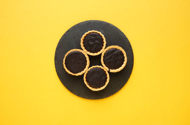 A picture of 4 chocolate tart on slate plate and yellow background. Food prepared for dessert. - Photo, Image