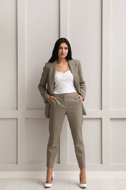 Full length portrait of beautiful woman in formal suit near light grey wall. Business attire - Foto, imagen