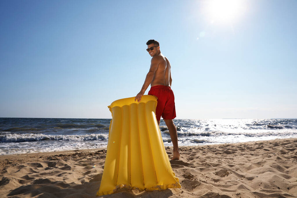 Man with yellow inflatable mattress at beach - Foto, imagen