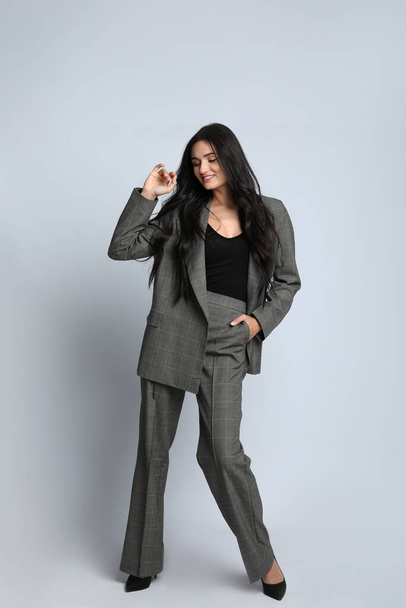 Full length portrait of beautiful woman in formal suit on light background. Business attire - 写真・画像