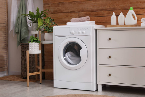 Laundry room interior with washing machine and stylish furniture - Fotoğraf, Görsel