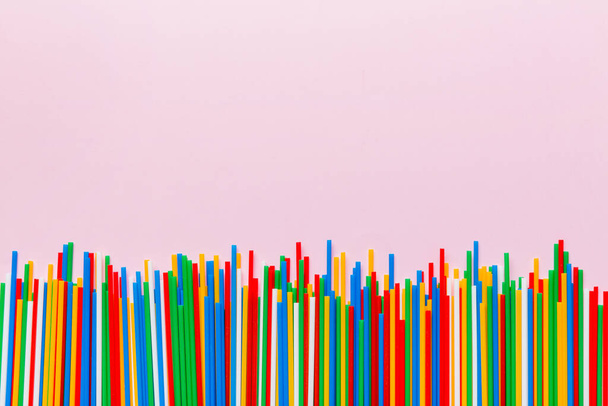 Куча разноцветных пластиковых соломинок для питья на цветном фоне, плоский уголок. Копирование пространства для текста. - Фото, изображение
