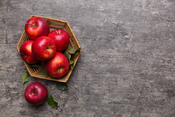 Зрізати садові яблучні фрукти з листям в кошику на дерев'яному столі. Плоский вигляд зверху з пробілом для копіювання
. - Фото, зображення