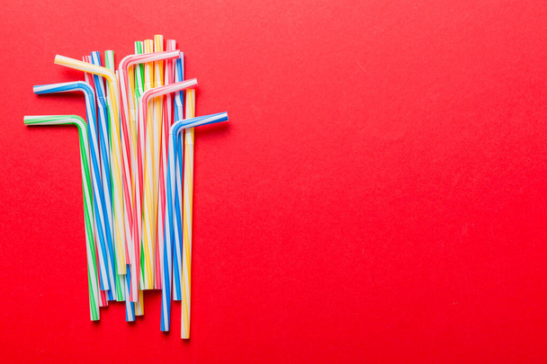 Heap of colorful plastic drinking straws on Colored background, flat lay. Copy Space for text. - Photo, Image