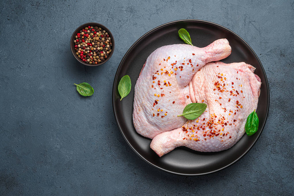 Fresh chicken legs with pepper and basil in a plate on a dark background. Top view, horizontal. - Фото, зображення