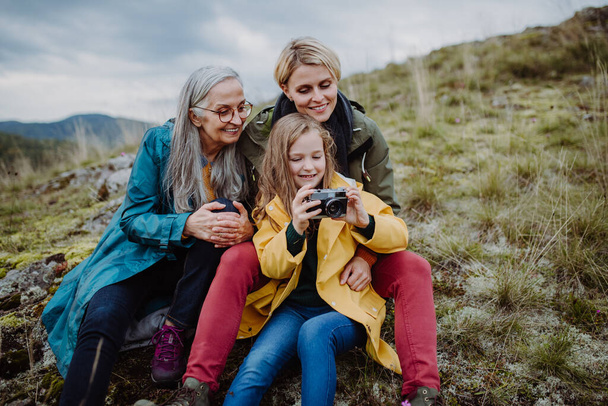 Small girl with mother and grandmother taking selfie pictures on top of mountain. - Valokuva, kuva