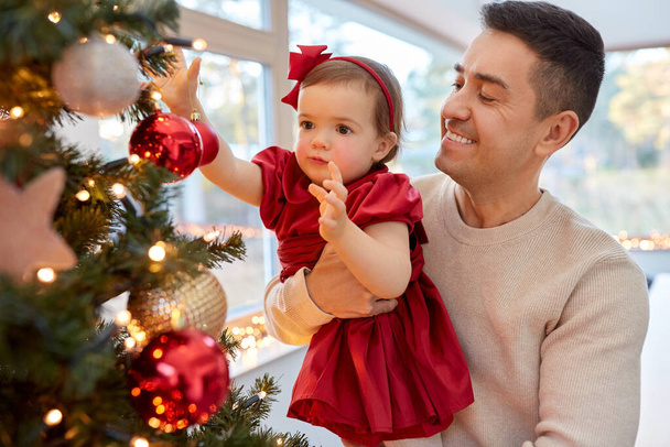 happy father and baby girl decorate christmas tree - Φωτογραφία, εικόνα